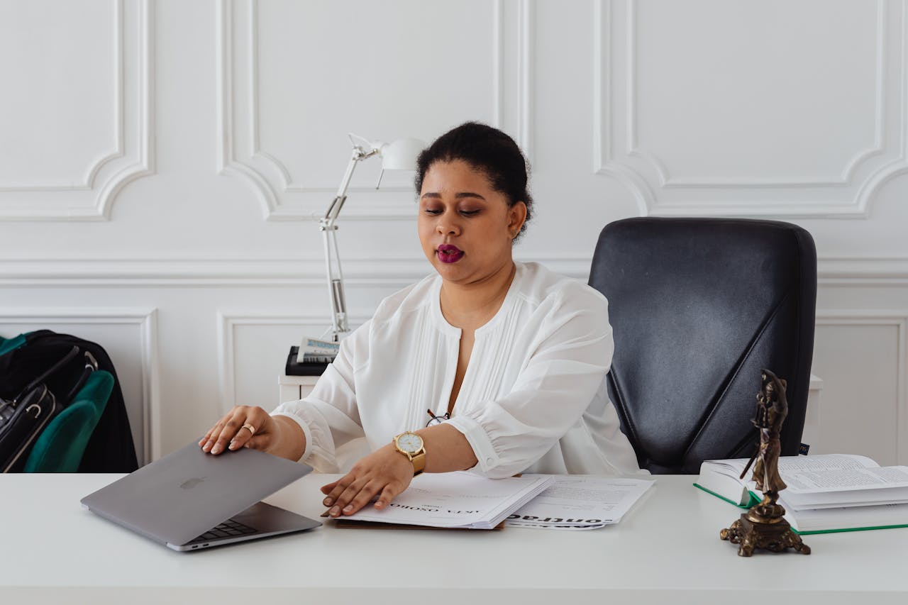 A Woman Sitting on the Black Leather Seat at the White Table with Laptop